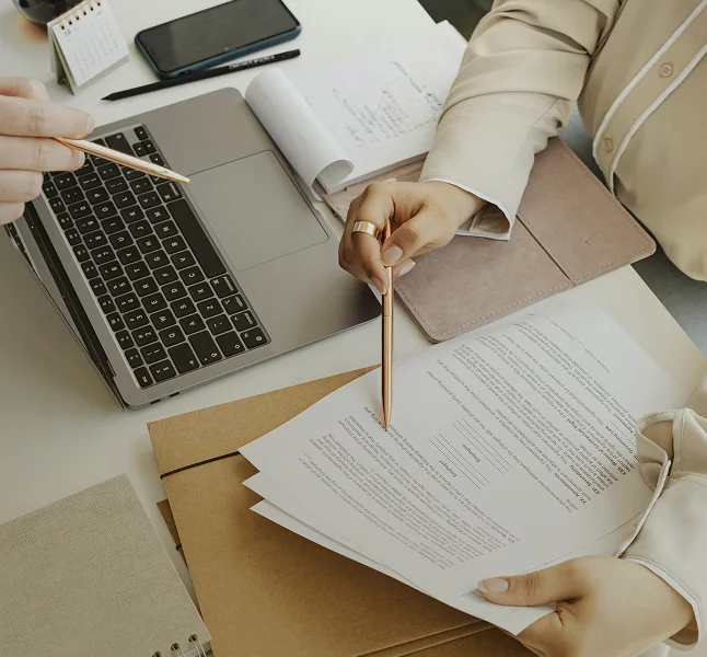 Professional reviewing permit documents beside a laptop